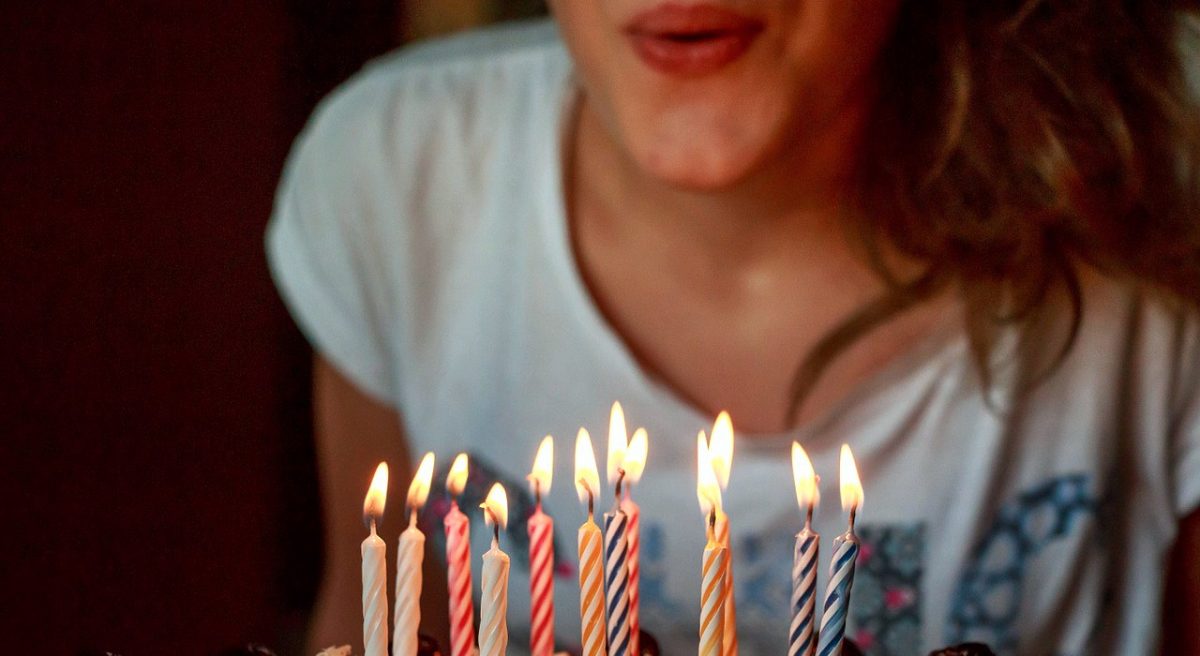 přání k narozeninám, dívka sfoukává svíčky z narozeninového dortu